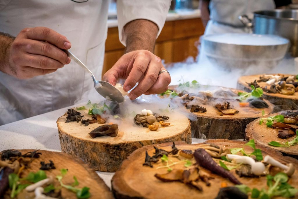 chef plating with wooden plates and different mushrooms